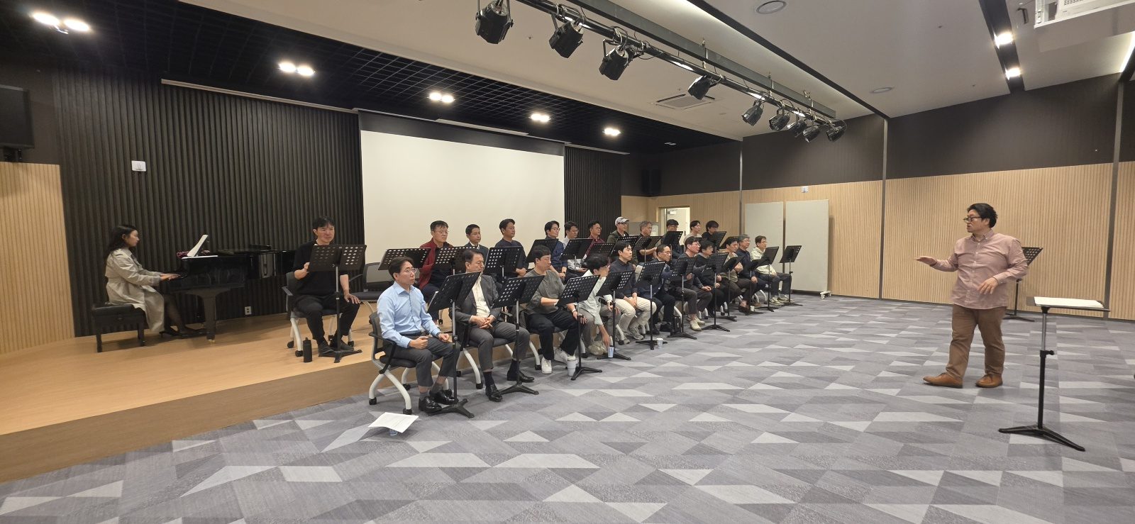 지휘자의 손짓에 맞춰 노래하는 단원들과 피아노 반주자