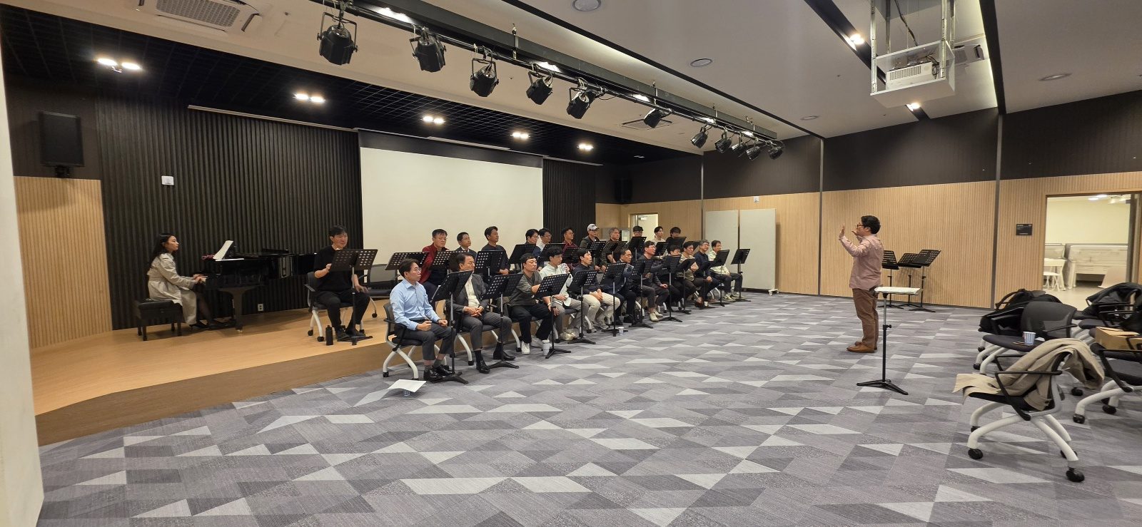 연습홀 앞쪽에 선 지휘자와 줄지어 앉은 단원들