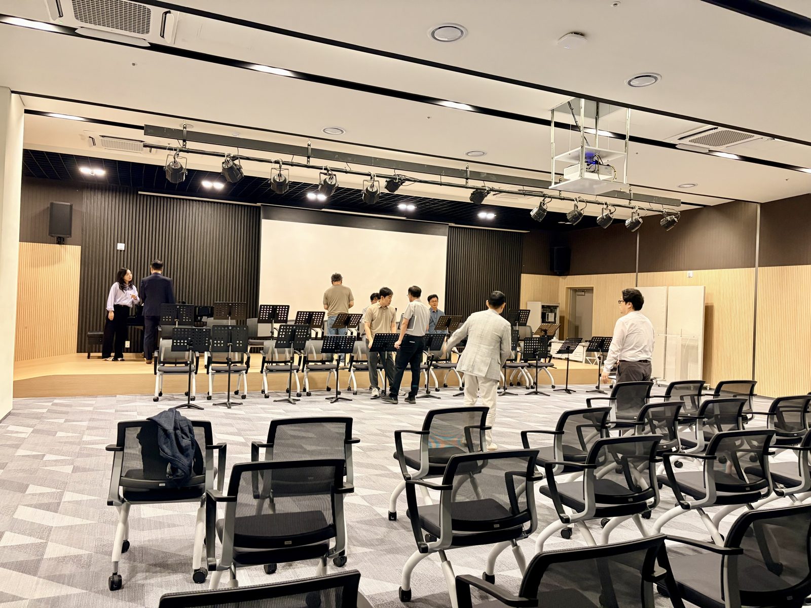 의자와 보면대가 놓인 연습홀에서 준비하는 단원들