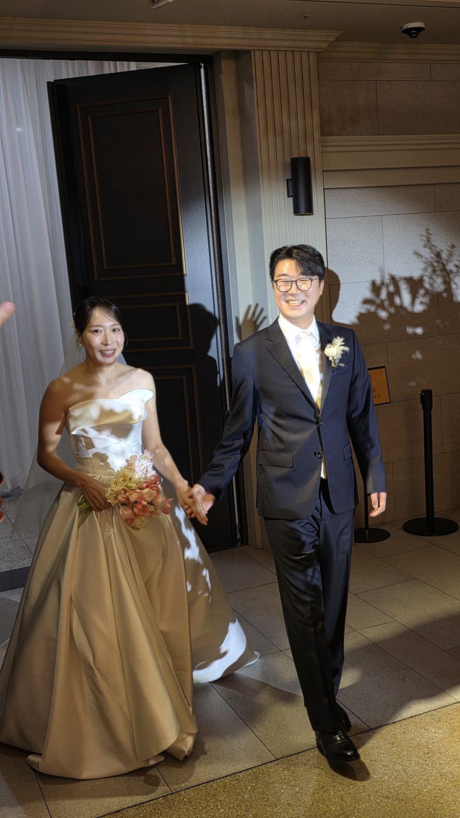 드레스를 갈아입은 신부와 신랑이 손을 잡고 걷는 모습
