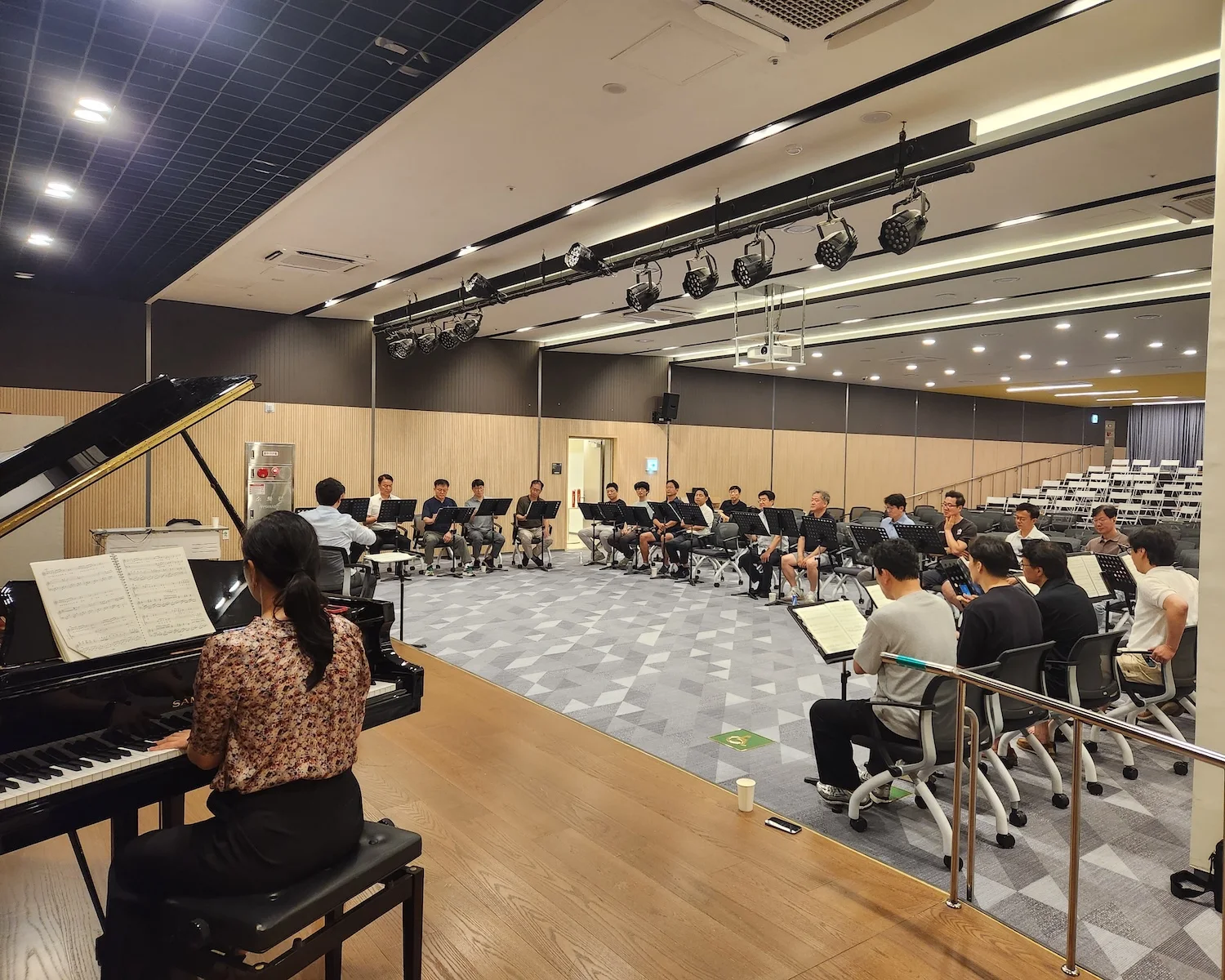 연습홀에서 피아노 반주와 함께 노래를 맞추는 단원들